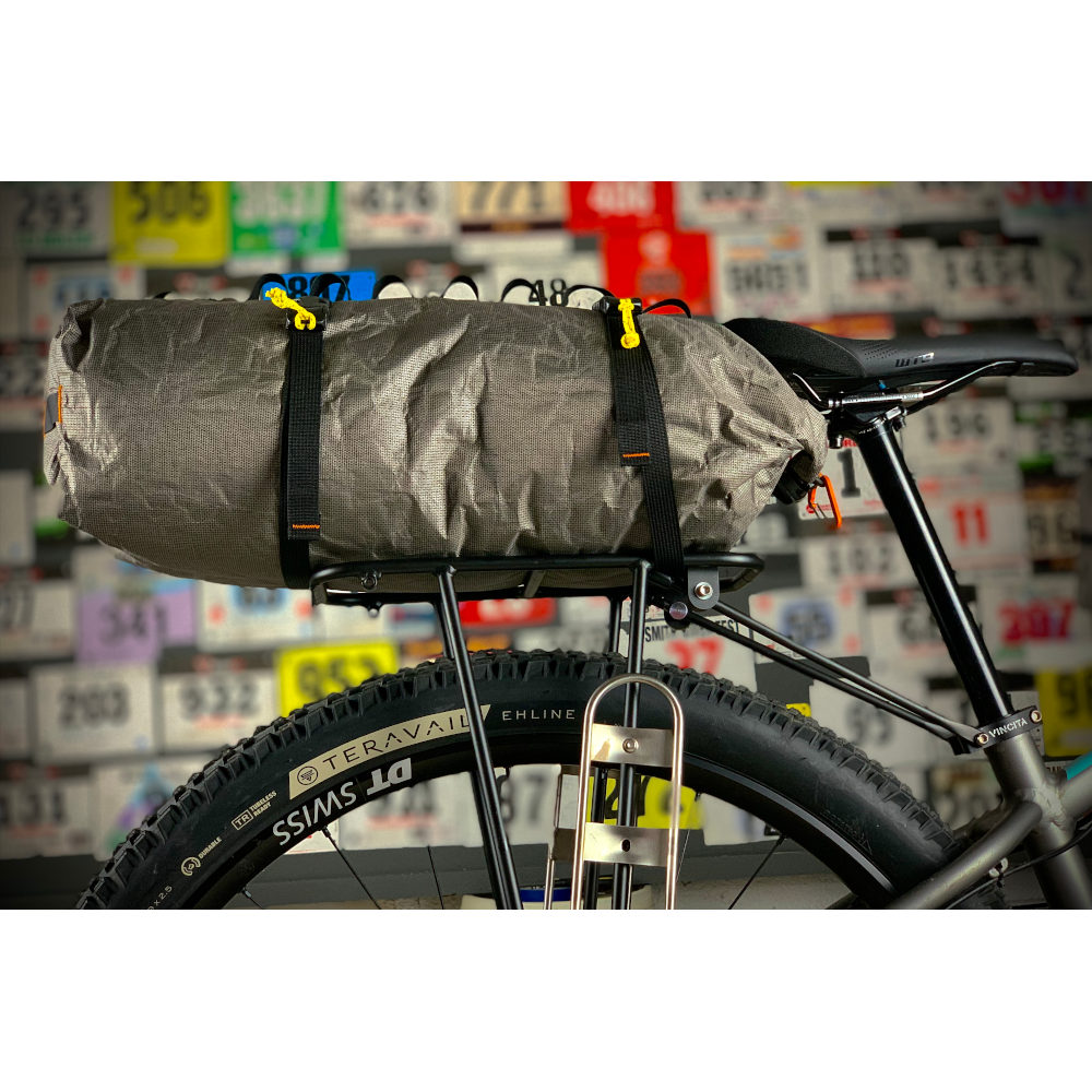 A set of bikepacking straps (sold seperately) secures an ULTRA 200X Dry back to the back roack of a bike.